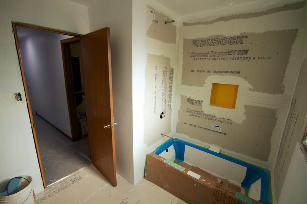 Badkamer in aanbouw met cementplaten en ingepakt bad