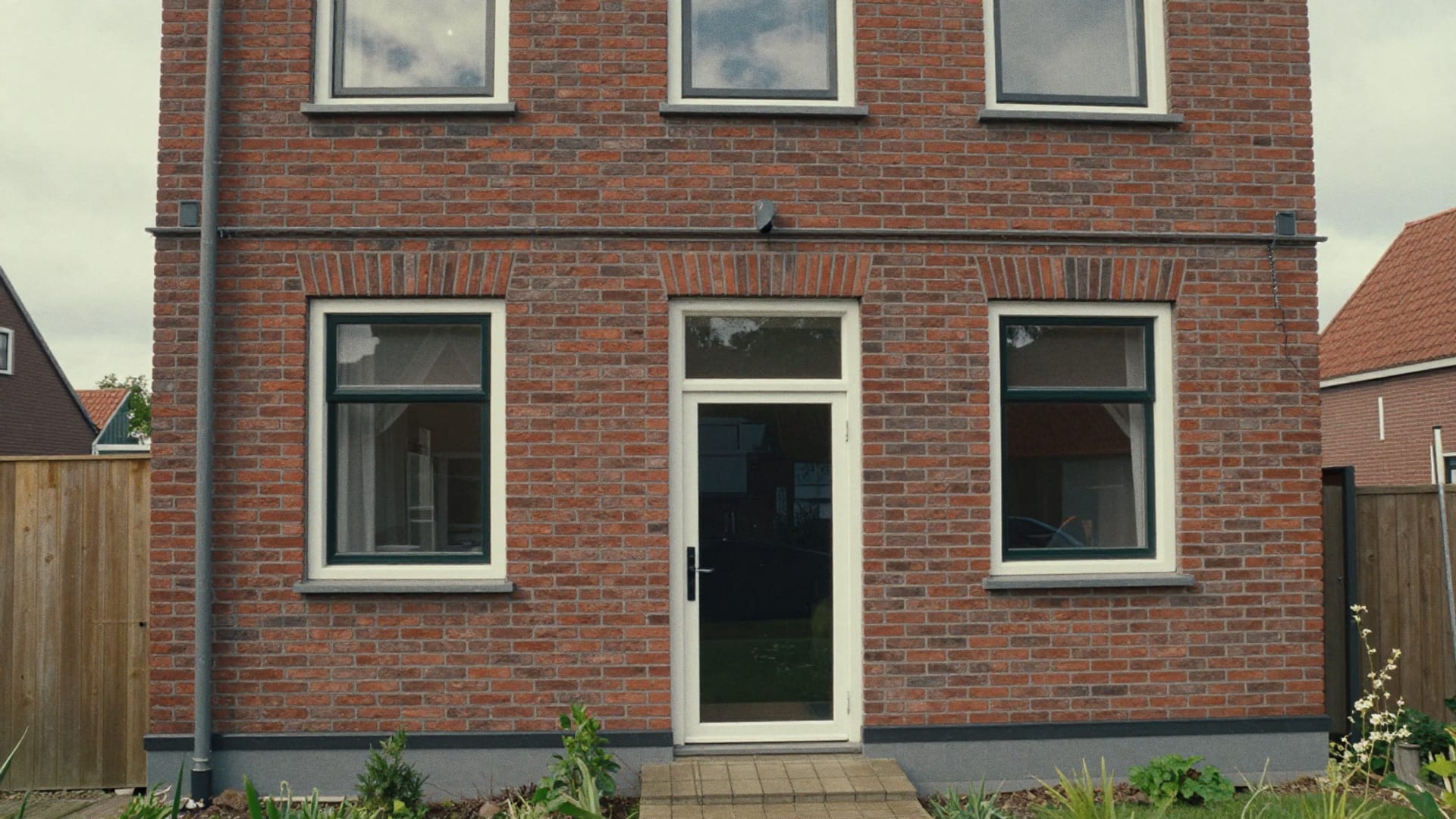 Bakstenen achtergevel van een woning met pas vernieuwde voegen, gezien vanuit de tuin