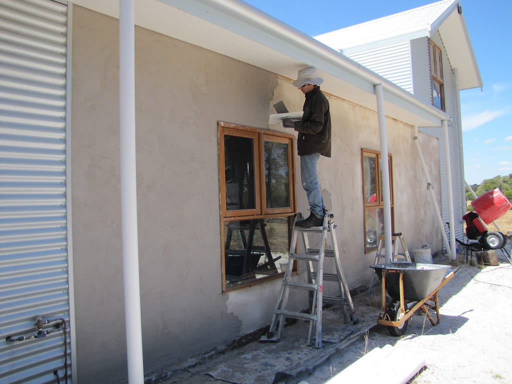 Stukadoor die met een spaan een muur stuukt